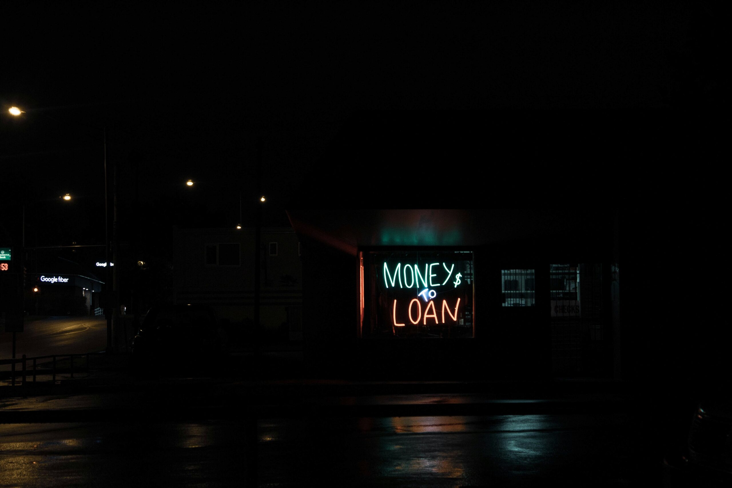 Dark street scene with neon sign reading ‘Money to Loan’ – symbolising financial pressure, debt and the mental strain money worries place on men