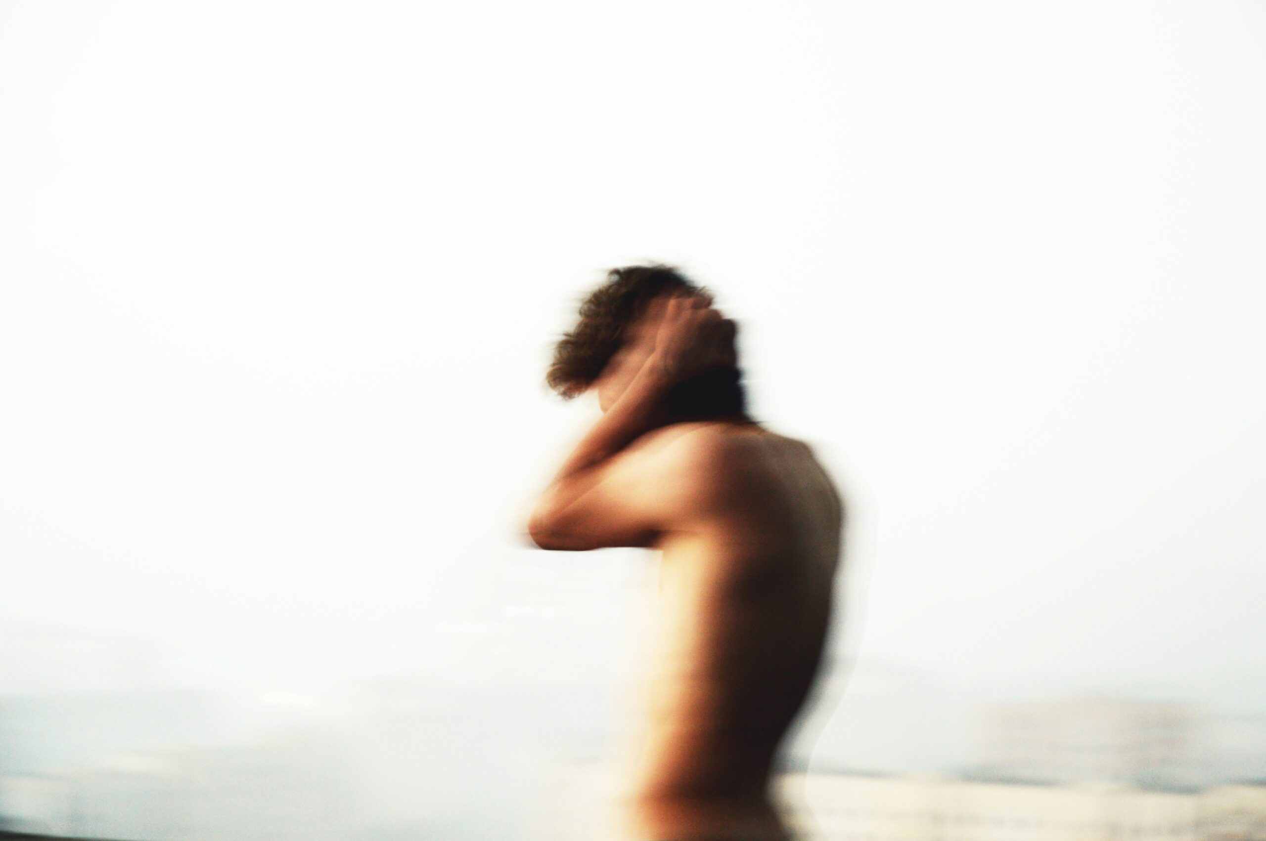 Blurred image of a shirtless man holding his head in distress – symbolising the inner turmoil and overwhelm often experienced with anxiety in men