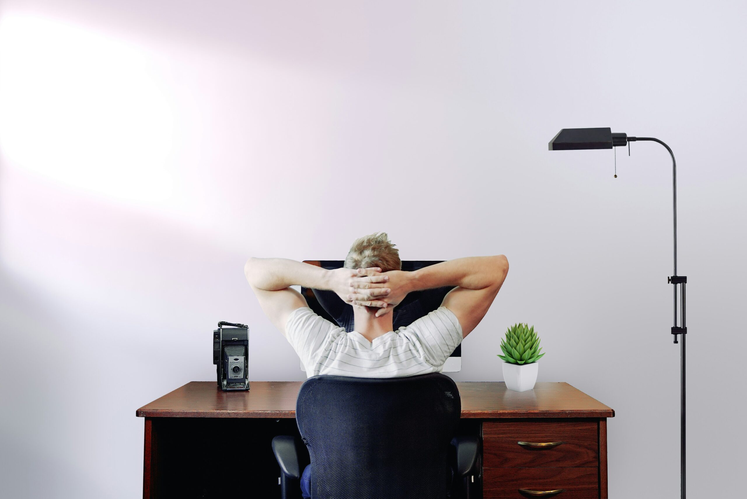 Man sitting at a desk with hands behind head, facing a computer screen – reflecting on how to choose the right therapist for his mental health needs