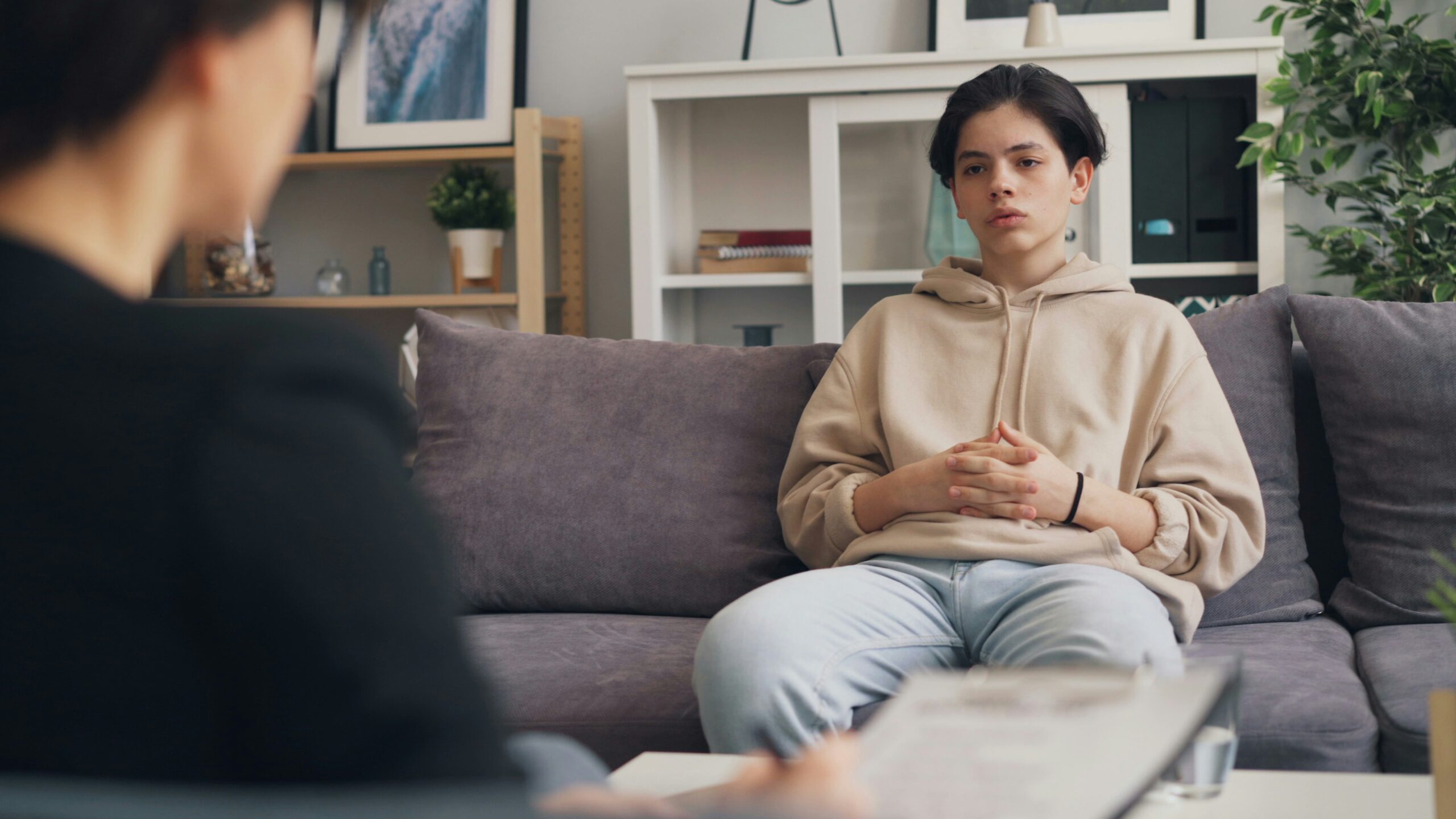 Teenage boy sitting on a sofa during a therapy session – representing how to open up and talk to a psychotherapist or counsellor