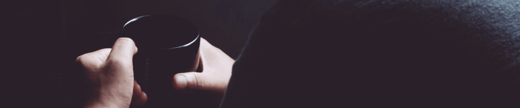 A man sits alone with a cup of coffee, symbolising the need to seek help