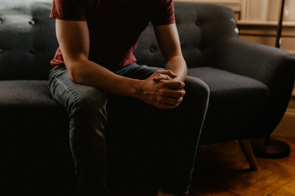A man sitting on a therapy sofa, ready to talk about how he's feeling