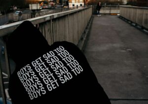 A man wearing a hoodie saying 'boys get sad too' - outlining why men also need support for their mental health.